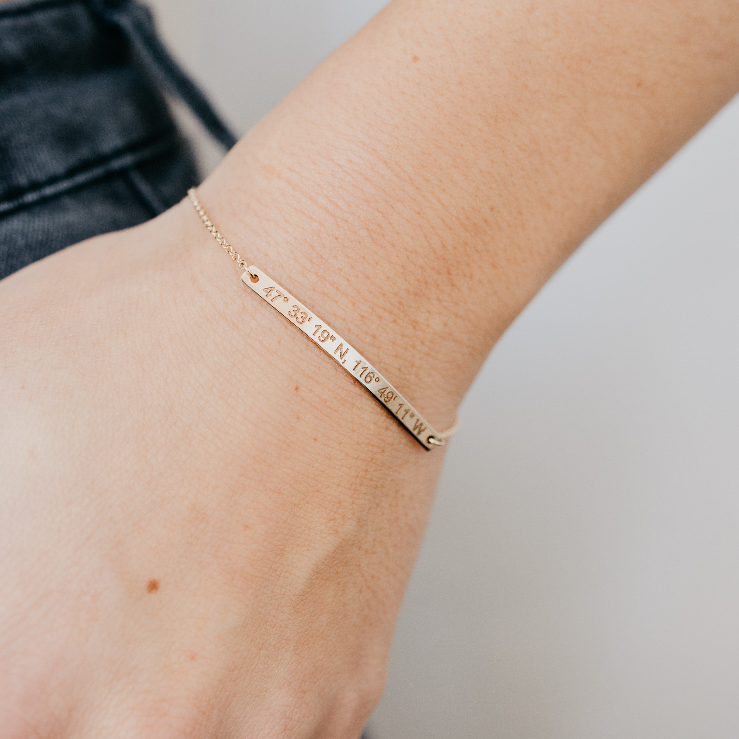 dainty coordinates bar bracelet by Lat & Lo in 14k gold-filled on model's wrist