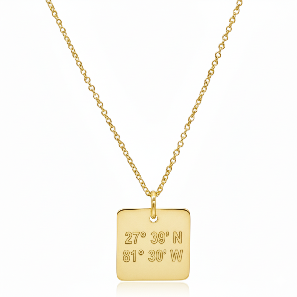 Gold necklace with a square pendant displaying coordinates on a white background