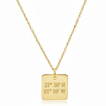 Gold necklace with a square pendant displaying coordinates on a white background