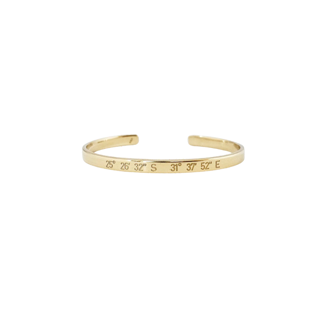 Gold bracelet with engraved coordinates on a white background
