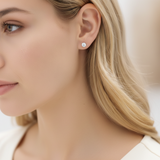 Close-up of a woman wearing diamond stud earrings with a blurred background